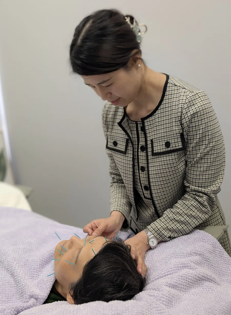 A practitioner performing cosmetic acupuncture on a client